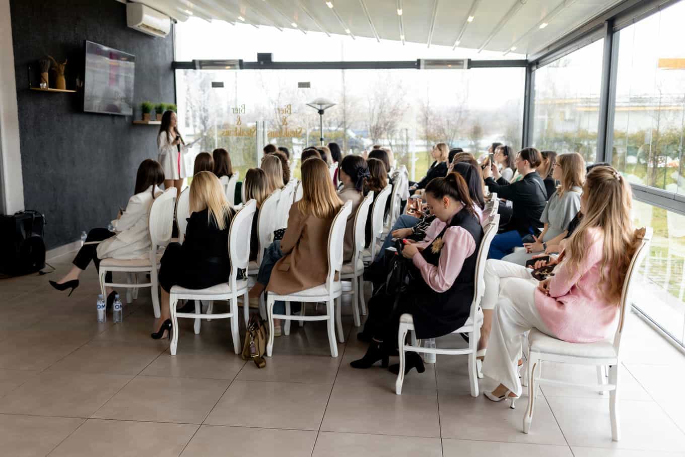 un-grupo-de-mujeres-estan-sentadas-en-sillas-y-una-lleva-una-camisa-rosa