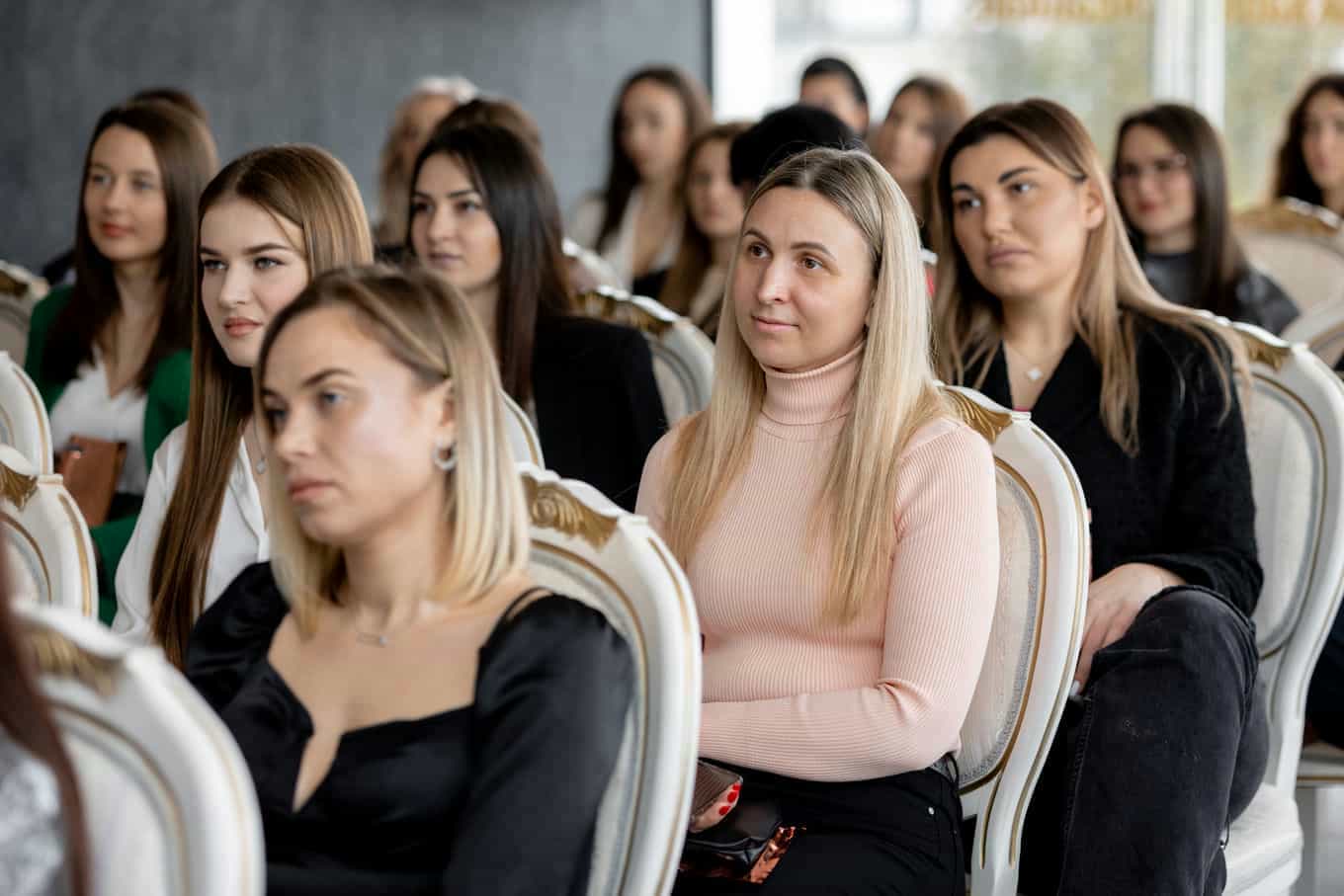 un-grupo-de-mujeres-estan-sentadas-en-una-fila-y-una-tiene-un-vestido-negro-en-el
